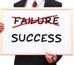 Person holding up a whiteboard displaying "Failure" crossed out in red with "Success" underneath