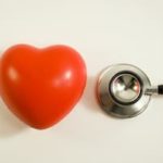 Red heart-shaped stress ball next to a stethoscope 