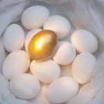 golden egg on top of a pile of regular eggs