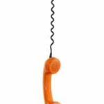 Orange telephone hanging down from telephone cord