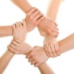 A group of hands holding each other's wrist in the shape of a circle