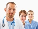 Male doctor and two female nurses posing behind him