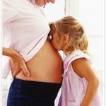 child kissing mother's pregnant belly