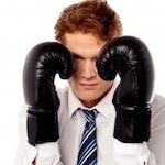 young man wearing a tie and boxing gloves close to his face