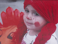 Little kid dressed up as a doll with a red braided wig for halloween 