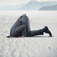 Man in suit putting his head in the sand