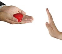 Man handing a small red heart over to someone refusing the offer