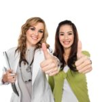 Female doctor and female patient standing next to each other giving a thumbs up
