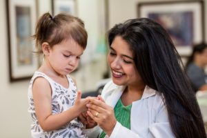Little girl showing injured finger to kind female doctor