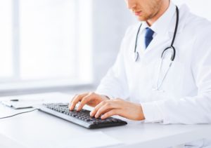 male doctor typing on a keyboard