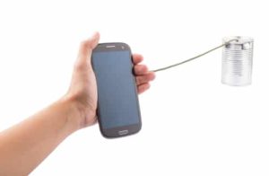 Person holding out a smartphone connected to a tin can with a string