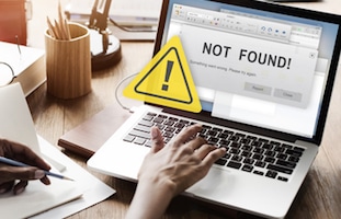 Person using laptop with a "Not Found!" warning sign displayed on the screen