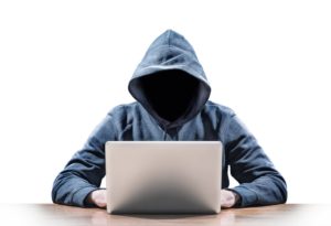 Hacker without a face wearing a hoodie, looking at a laptop