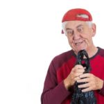 Elderly man wearing a sideways baseball cap making a funny face