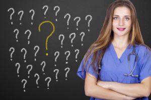 Female nurse standing in front of chalk board with question marks on it