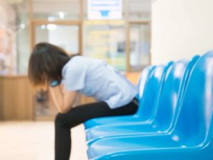 little girl waiting impatiently in waiting room on blue chairs