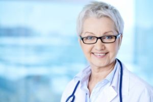 Aligned right headshot of older female doctor against blurry blueish background