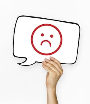 Person holding up a speech bubble with a red frown face in it