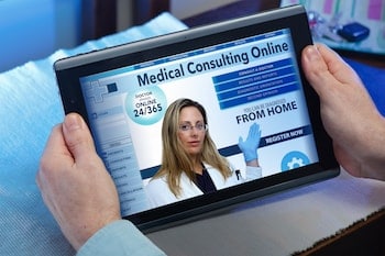Person holding iPad with a "Medical Consulting Online" ad on screen