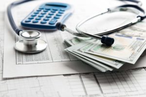 a stethoscope, calculator, and 100 dollar bills representing Healthcare marketing budget