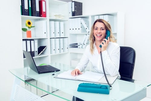 Female medical scheduler talking on the phone at her desk