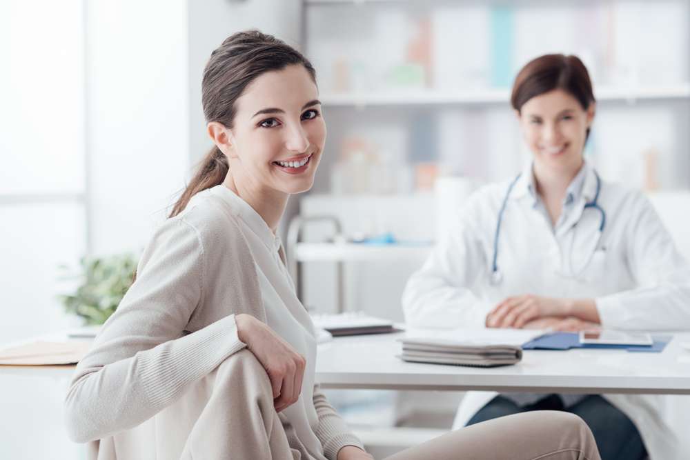 Female patient sitting across from female doctor, both smiling