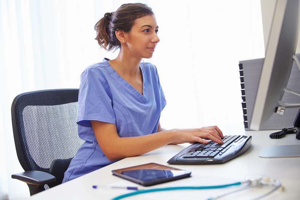 Female nurse sitting at a desk typing on a computer