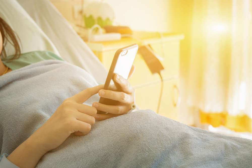patient in hospital bed with phone