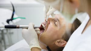 man having his teeth cleaned by dentist
